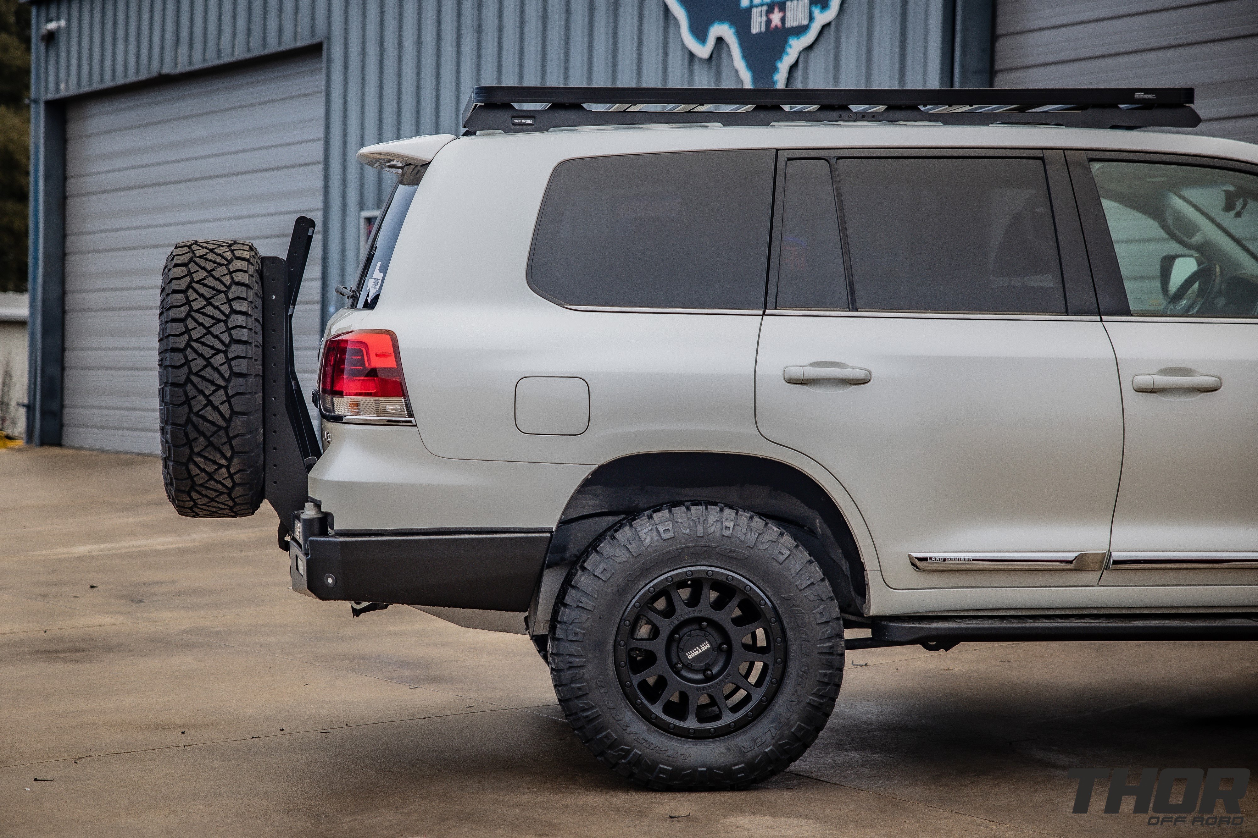 2021 Toyota Land Cruiser in Silver with OME BP-51 Suspension Kit, Method 305 18x9" +25 Wheels, Nitto Ridge Grappler 285/70R18 Tires, Slee Off-Road Front Bumper, Baja Designs S2 Driving Lights, Baja Designs S8 20" Combo Light Bar, Warn Zeon 12S Winch, Slee Off-Road Rear Bumper with Tire Carrier and Roof Rack, Long Range America 40 Gallon Auxillary Fuel Tank, Slee Off-Road Rock Sliders, Front Runner Slimline II Roof Rack Kit. Slee Off-Road Skid Plate System, Slee Off-Road Second Battery System, ARB Twin Compressor Kit