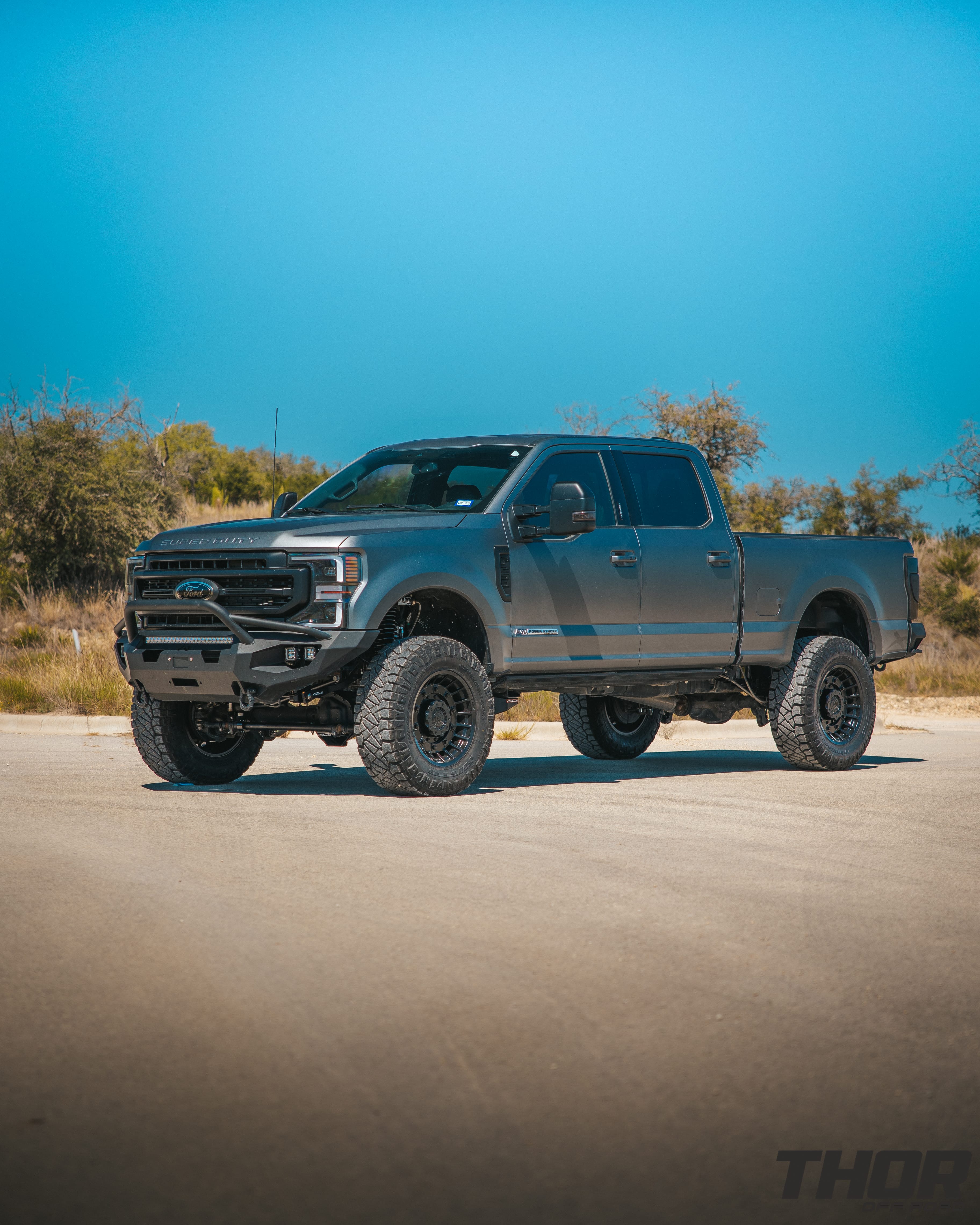 2022 Ford F-250 Super Duty Lariat in Grey with Carli 5.5" Backcountry Suspension Kit, Carli High Mount Steering Stabilizer, Carli Low Mount Steering Stabilizer, Carli Radius Arms, Carli Torsion Sway Bar, Carli Full Rear Spring Replacement, Carli Long Travel Air Bags, 20x10" Miltia Wheels, AMP Research Steps, Retrax Pro Bed Cover, Fab Four Matrix Pre-Runner Front Bumper, Go Rhino BR20.5 Rear Bumper, Rigid D Series Flood Lights